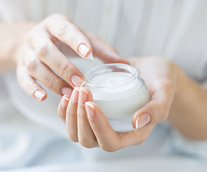 Woman holding jar of cosmetic cream