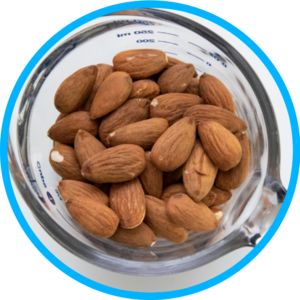 An overhead view of whole almonds inside a glass measuring container.